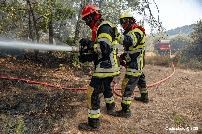 Pompiers en tenue de protection tenant un tuyau
